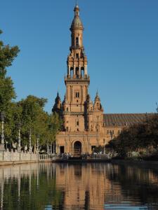 un gran edificio con una torre de reloj junto a un cuerpo de agua en Apartamentos cruz roja B, en Sevilla