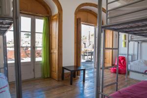 a room with a bed and a table and windows at This Is Lisbon Hostel in Lisbon