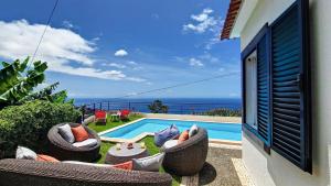 um pátio com cadeiras e uma piscina com o oceano em Villa Liana by LovelyStay em Ponta do Sol