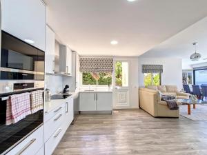 uma cozinha com armários brancos e uma sala de estar em Villa Liana by LovelyStay em Ponta do Sol