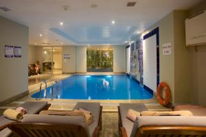 a large swimming pool in a room with chairs and a couch at Ramada By Wyndham İstanbul Taksim in Istanbul
