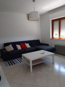 een woonkamer met een blauwe bank en een witte tafel bij Villa Dormi'RE Sul Golfo in Su Forti