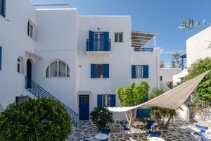 a white building with blue doors and a hammock in front at Livadia Seaside Studios 1 in Parikia