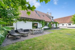 a patio with chairs and a table in a yard at d'Oude Schaapskooi, de luxe vakantiehoeve in Damme in Damme