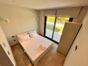 a small bedroom with a bed and a large window at Sakin ve huzurlu bir tatil için… in Çeşme