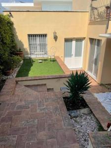 een achtertuin met een patio en een tuin met gras bij Casa Gelsomino in Forte dei Marmi