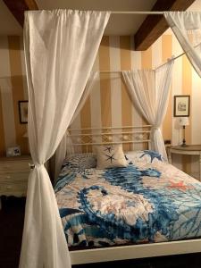 um quarto com uma cama de dossel e cortinas brancas em Casa Gelsomino em Forte dei Marmi