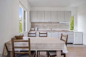 een keuken met witte kasten en een tafel en stoelen bij Apartments Zlarin in Zlarin