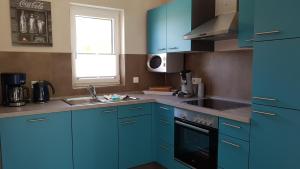 eine Küche mit blauen Schränken, einem Waschbecken und einem Fenster in der Unterkunft Premiumferienhaus Ankaa in Hasselfelde