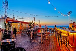 a bar with tables and chairs on a deck at Carlton Tel Aviv Hotel – Luxury on the Beach in Tel Aviv
