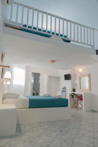 a white bedroom with a bed and a staircase at Sfiga villas in Perissa