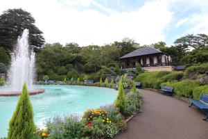 une fontaine dans un jardin avec un bâtiment en arrière-plan dans l'établissement mei Hakone, à Hakone