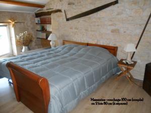um quarto com uma cama grande e uma parede de pedra em MARAIS POITEVIN gite "volets bleu clair" pêche ,barque, vélos, wifi, linge, cheminée, cuisine, terrain de boules em La Taillée
