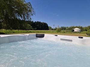 a jacuzzi tub with water in a yard at Cranfield Retreat & Glamping - Yurt & Shepherds Hut in Long Melford