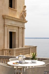 a table and chairs on a balcony next to the water at Hospes Maricel y Spa, Palma de Mallorca, a Member of Design Hotels in Cas Catala