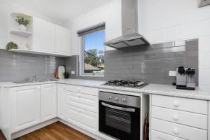 a white kitchen with a stove and a window at Gateway Retreat near Flinders Uni & Hospital in Sturt