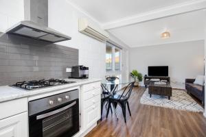 a kitchen with a stove and a living room at Gateway Retreat near Flinders Uni & Hospital in Sturt