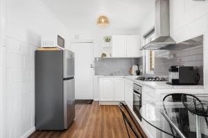 a kitchen with a stainless steel refrigerator and a table at Gateway Retreat near Flinders Uni & Hospital in Sturt +5 photos