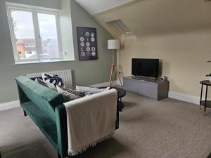 a living room with a green couch and a television at Charming 1-Bed loft in Caerleon in Newport