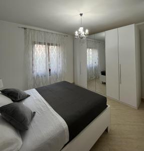 Habitación blanca con cama grande y lámpara de araña. en Clò House, en Fondi