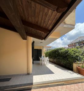 un patio con sillas blancas y techo de madera en Clò House, en Fondi