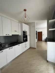 cocina con armarios blancos y suelo de baldosa en Clò House, en Fondi