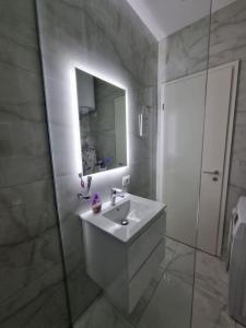 uma casa de banho branca com um lavatório e um espelho em Anika Home Tirana 1 em Tirana