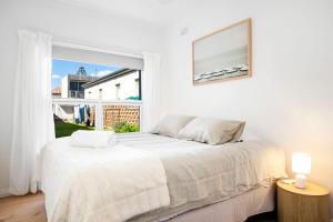a white bedroom with a bed and a large window at Luxury Beachfront Retreat on Henley Beach Esplanade in Henley Beach South