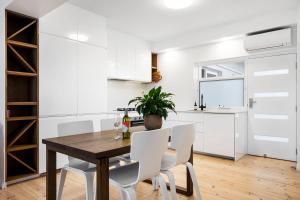 a kitchen and dining room with a wooden table and white chairs at Luxury Beachfront Retreat on Henley Beach Esplanade in Henley Beach South