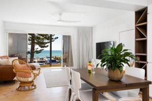 a living room with a dining room table with a plant at Luxury Beachfront Retreat on Henley Beach Esplanade in Henley Beach South