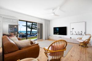 a living room with a couch and a tv at Luxury Beachfront Retreat on Henley Beach Esplanade in Henley Beach South