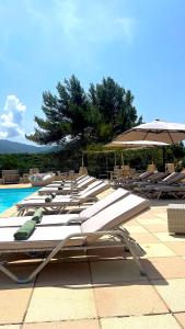 - une rangée de chaises longues et un parasol à côté de la piscine dans l'établissement Hotel & Appartements Acqua Dolce, à Porticcio