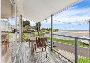 a porch with a table and chairs and a view of the ocean at Beachfront Gerroa in Gerroa