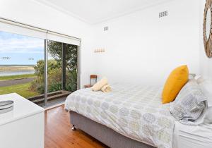 a white bedroom with a bed and a large window at Beachfront Gerroa in Gerroa