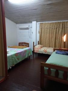 Cette petite chambre comprend 2 lits et une fenêtre. dans l'établissement La casona, à Puerto Iguazú