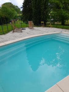 une grande piscine bleue avec 2 chaises longues dans l'établissement chambre du jura, à Saint-Germain-lès-Arlay