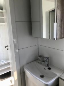 a white bathroom with a sink and a mirror at Mobilheim im Amazonas Camp - viel Platz und Komfort in Loitz