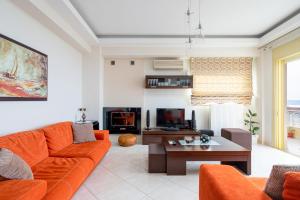 a living room with an orange couch and a tv at Artemisia Sunset View in Sitia