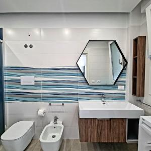 a bathroom with a sink and a toilet and a mirror at Brezza Salentina Aparthotel in Torre San Giovanni Ugento