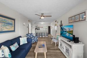 een woonkamer met een blauwe bank en een tv bij Out To Sea - Oceanfront 2 Bedroom, 2 Bath Condo in North Topsail Beach