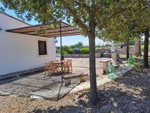 a patio with a table and chairs and a tree at Trulli Cibelis in Noci
