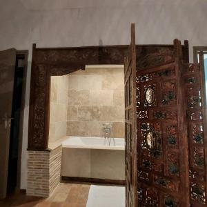 a bathroom with a bath tub and a wooden door at Maison d'hôtes de La Roche Tabary 