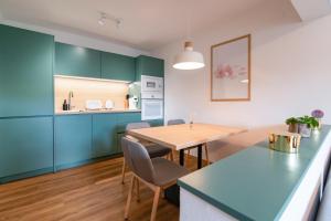 a kitchen with green cabinets and a wooden table at MIZU APARTMA VAS LIPA OLIMJE in Podčetrtek