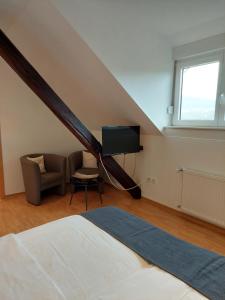 1 dormitorio con 1 cama, TV y silla en Weingut Licht-Stadtfeld, en Brauneberg
