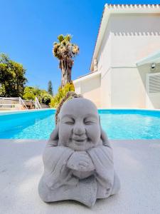 une statue de buddha assise en face d'une piscine dans l'établissement La Costa B&B, à Flumini di Quartu