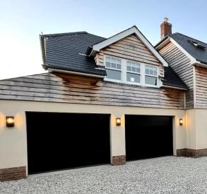 a house with two garage doors in a driveway at LymingtonBnB in Lymington