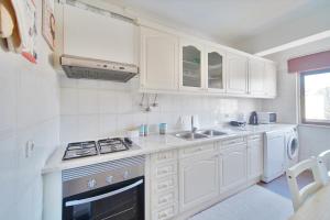 a white kitchen with a stove and a sink at Amazing Apartments in Agualva