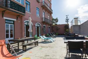 un patio avec des tables et des chaises à côté d'un bâtiment dans l'établissement This Is Lisbon Hostel, à Lisbonne