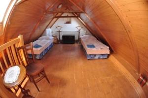 an attic room with two beds and a chair at Slavonice - Čapí dům in Slavonice