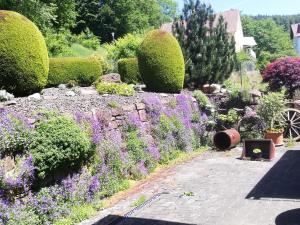 un jardín con flores púrpuras y una pared de piedra en Ferienwohnung Traumblick, 